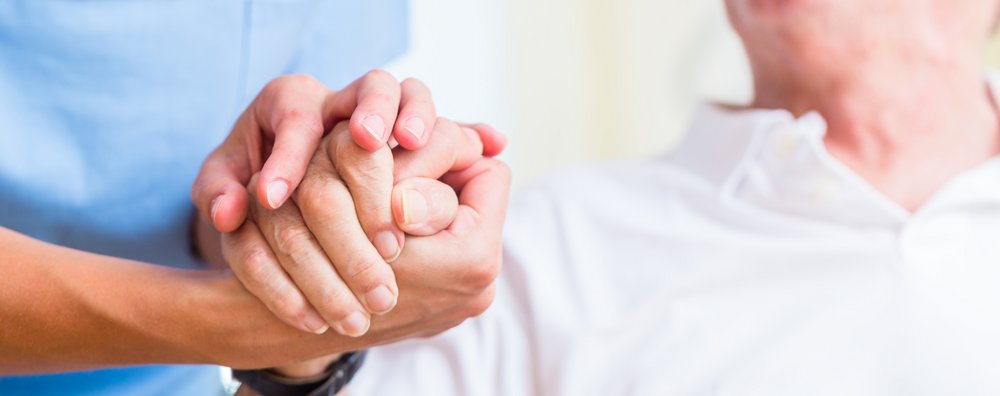 Altenpflegerin hält Hand von Senior in Altersheim