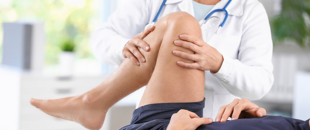 Arzt behandelt Patient am Knie