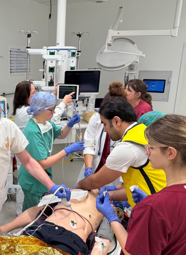 Ein Team aus Ärzten und Pflegern üben Abläufe an einer Übungspuppe auf einer Liege