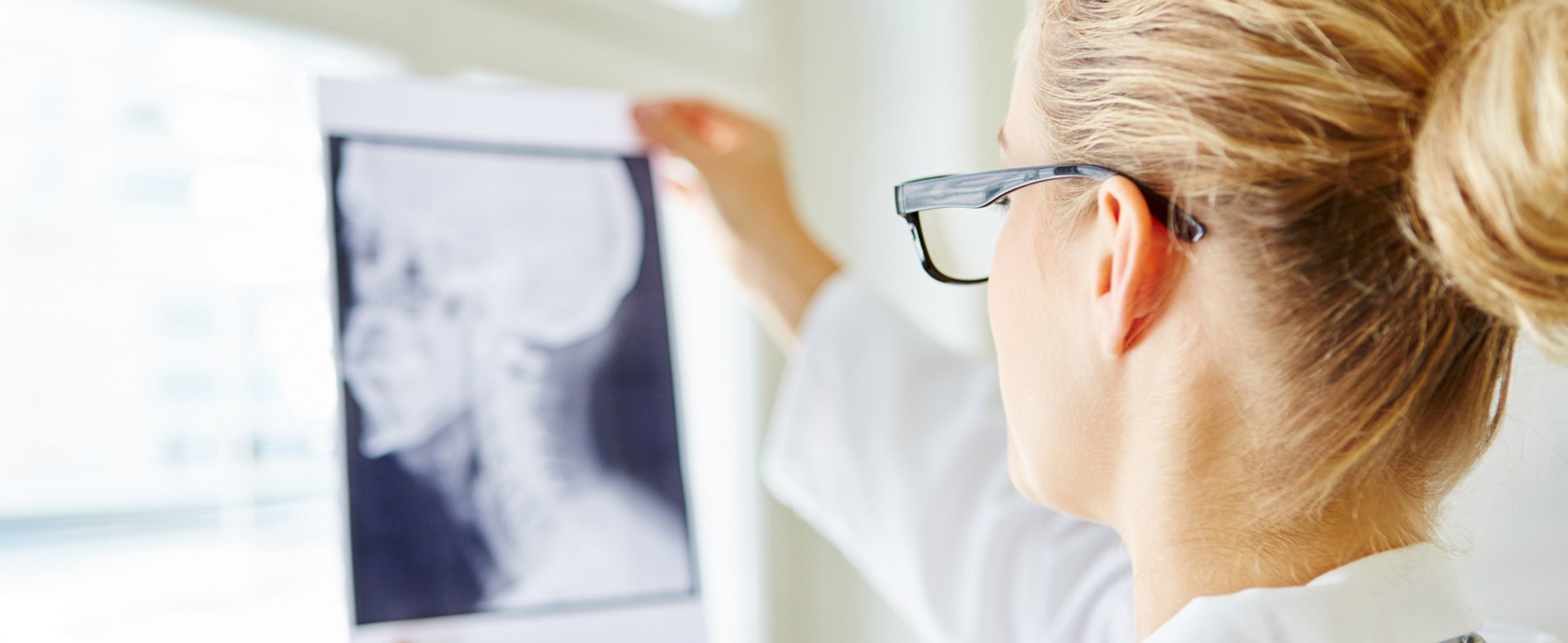 Eine Ärztin hält ein Röntgenbild eines Kopfes hoch
